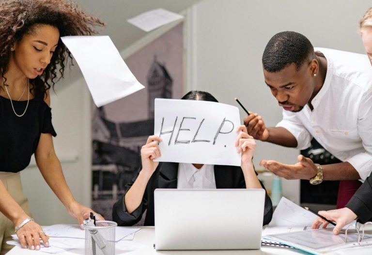 Gestresste Büroatmosphäre mit einem Team, das Hilfe anbietet und Papier wirft.