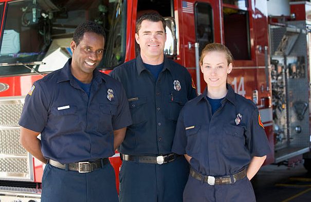 Vier junge Menschen lächeln, stehen arm in arm in einem modernen Raum.
