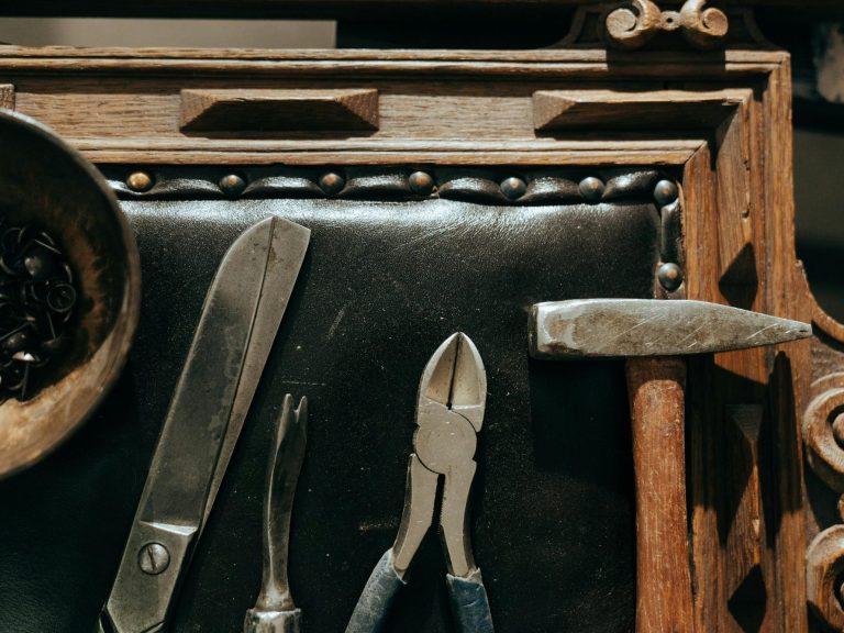 Werkzeuge auf einer Holzunterlage: Messer, Zange, Hammer und eine Schale.