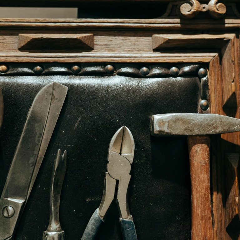 Werkzeuge auf einem Holzuntergrund: Zange, Hammer und verschiedene Klingen.